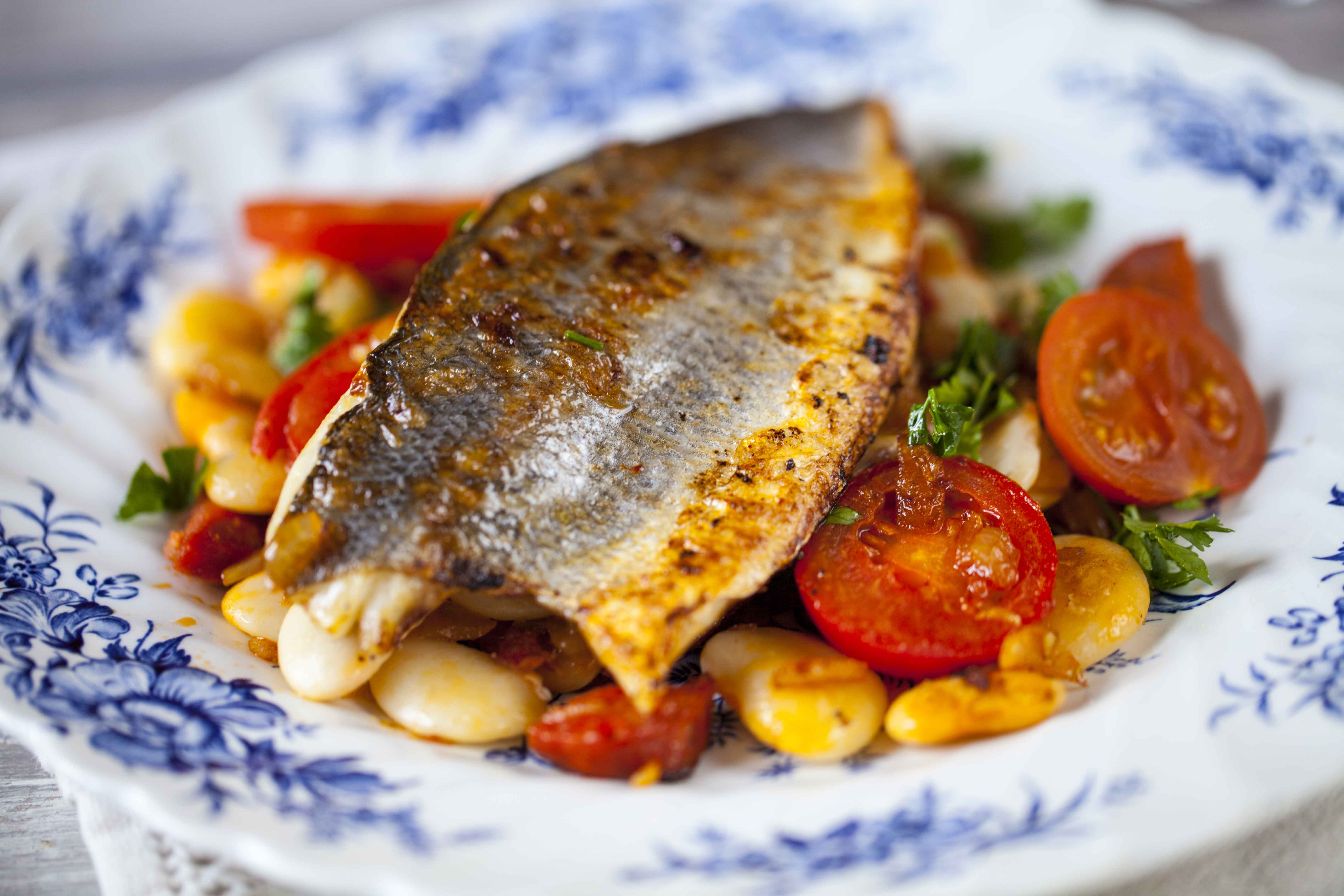 Roasted fish served on a plate with colorful roasted vegetables